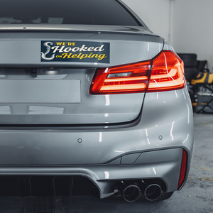 Were_Hooked_On_Helping_Others_WhiteBumperSticker-GrayCar_Mockup.png