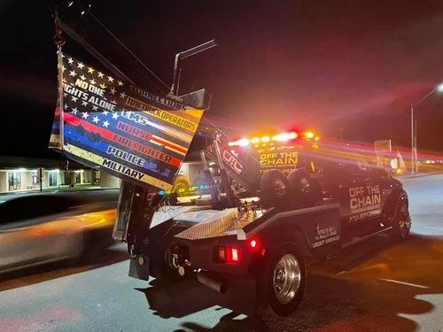 Tow truck at night with its lights on, flying flags