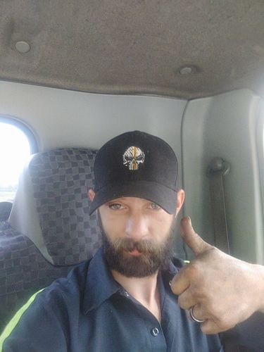 Tow operator in his truck wearing a black Tow Lives Matter cap