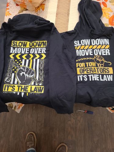 Two Slow Down Move Over hoodies laid out on a floor