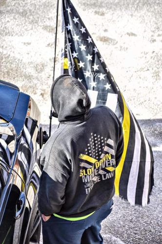 Customer in a Slow Down Move Over hoodie next to a thin yellow line flag