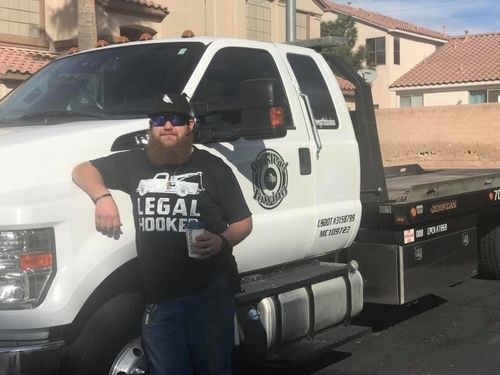 Tow operator leaning on his flatbed tow truck