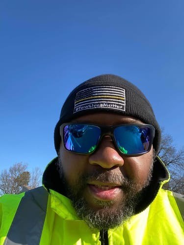 Tow operator in a high-visibility jacket wearing a Tow Lives Matter beanie