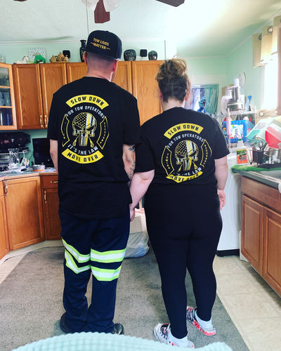 Couple wearing matching Slow Down Move Over shirts, seen from behind